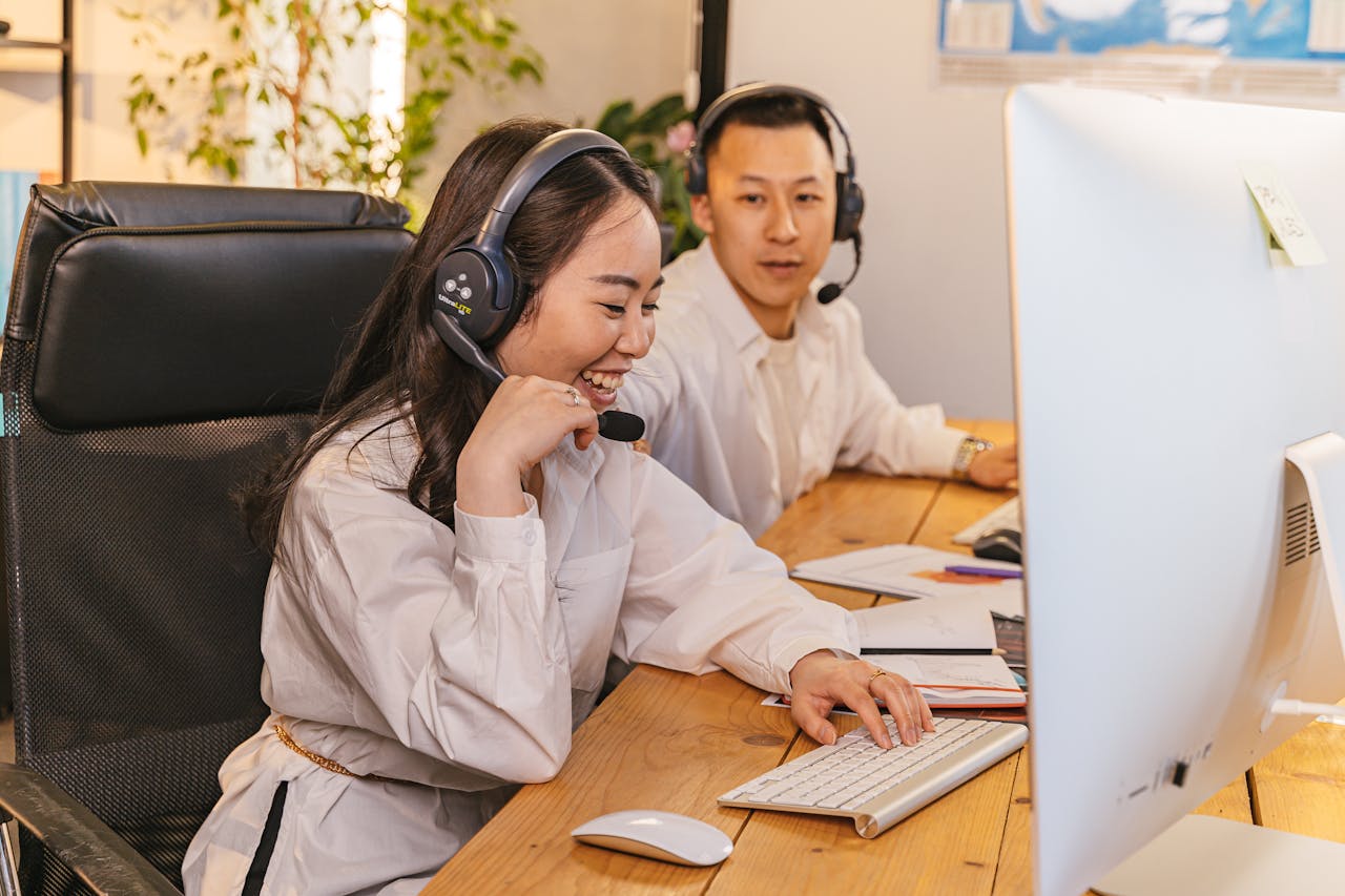 Two call center agents working together, focused and engaged at their desks, communicating via headsets.